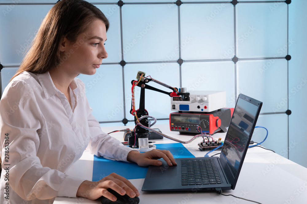 Canvas Prints A young woman writes an algorithm for the robot arm. Science Research Laboratory for Robotic Arm Model. Computer Laboratory