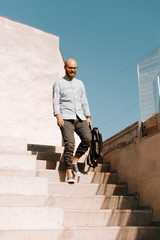 Photo of handsome bearded hispter guy, wlaking down on stairs, posing, student concept