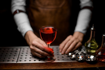 Bartender serving a red alcoholic cocktail in the glass