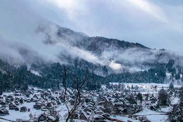 clouds descending a mountain in a snowed landscape