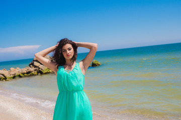 Fototapeta na wymiar Young girl on the beach in summer in a beautiful dress 