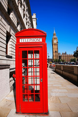 Fototapeta na wymiar Iconic Red Telephone Booth and Big Ben Clock Tower over blue sky.