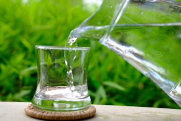 glass of water on green background of grass