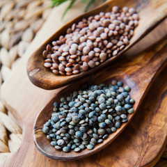 Brown and Green Lentils on wooden spoons.
