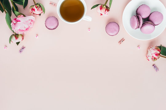 Top view of macaroons with a Cup of tea and peonies. - Powered by Adobe