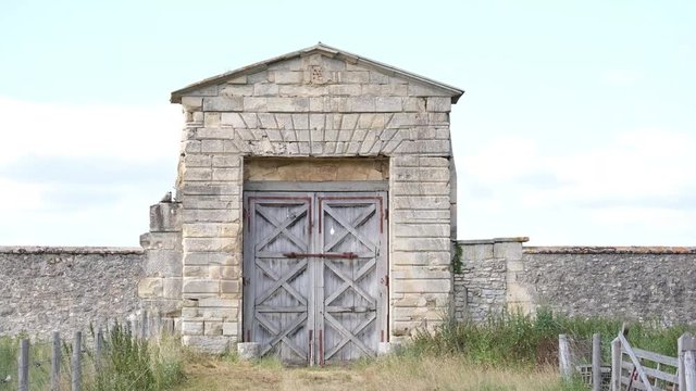 Grande porte en bois entour&eacute;e de pierres et herbes (4K) ciel blanc VFX
