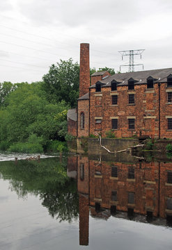 thwaite mill in knostrop leeds built in 1825 on an island between the river aire and calder navigation canal reflected in the water and surrounded by trees
