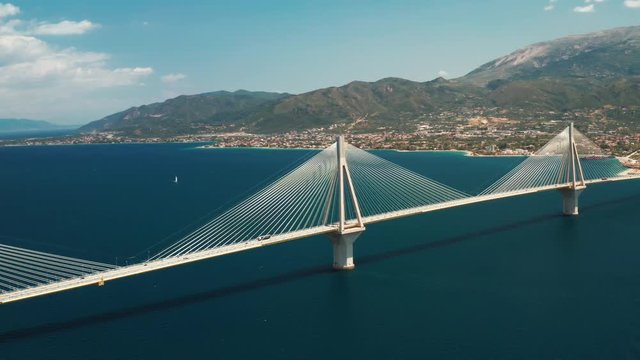 Beautiful large bridge for motorway across sea in city of Patras, Greece, aerial view of drone slide turn . Sophisticated, beautiful design of the automotive bridge in sea in the summer