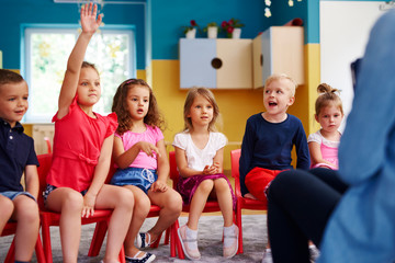 Girl raising her hand to ask question in classroom