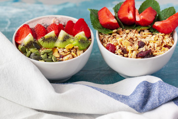 Bowl of homemade granola with yogurt and fresh berries on wooden background