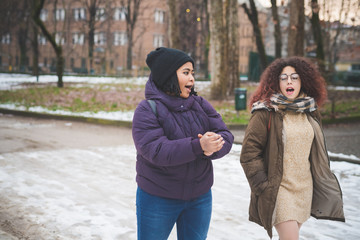 two multiracial young women walking and talking in the street