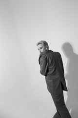 Stylish young woman in a suit in the studio on a white background. Short haircut. Black and white photo.