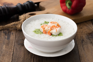 white bowl of Shrimp porridge, Thai rice soup with shrimp (Khao Tom Koong) on wood