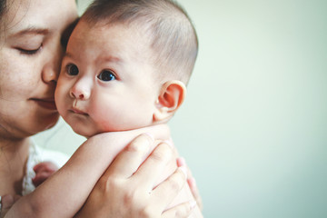 Asian girl mother hugging and kissing her baby son