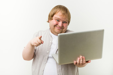 Caucasian plus size man holding a laptop cheerful smiles pointing to front.