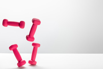 pink bright dumbbells flying in air on white background with copy space