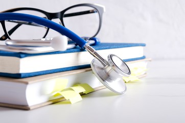 Fototapeta Glasses, medical books and professional stethoscope on the white desk obraz