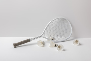 white badminton shuttlecocks near white racket on white background
