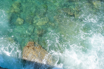 Ocean coast. Calm waves crash against stones on a quiet sunny day.