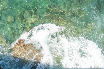 Ocean coast. Calm waves crash against stones on a quiet sunny day.