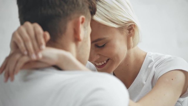 beautiful young couple embracing, smiling and kissing at home