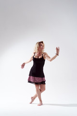 Photo of long-haired blonde looking to side engaged in dancing in studio on empty white background