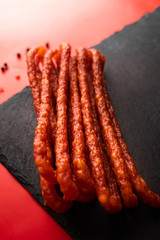Spicy sausages. Thin sausages with spices on a red background