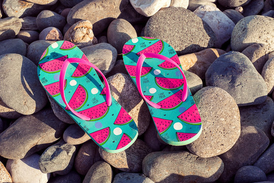 Beach Slippers on the background of the blue sea and pebble beach