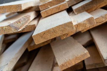 a pile of wooden planks lying on the street. wooden building material. A lot of wooden planks lying on the ground. Wooden sticks are lying on the ground. lumber lying on the street. Pine board cut