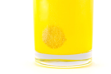 Yellow effervescent tablet dissolves in a glass of water
