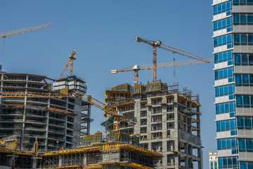 High-rise buildings with yellow cranes and scaffolding at construction site