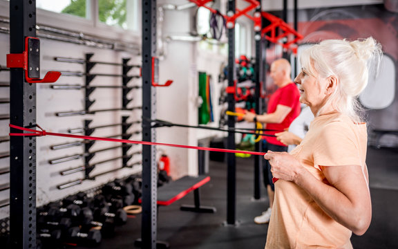Senior people with trainer using resistance band doing exercises at the gym