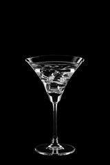 Martini glass with ice cubes isolated on black background
