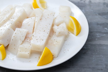 raw squid with pepper and fresh lemon on white plate