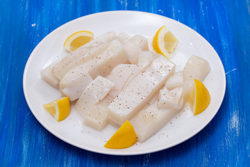 raw squid with pepper and fresh lemon on white plate