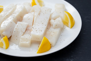 raw squid with pepper and fresh lemon on white plate