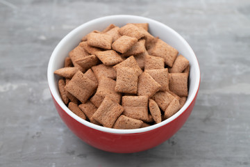 Chocolate pillows in red bowl on ceramic background