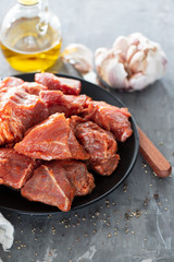 raw pork in marinate on black plate on ceramic background