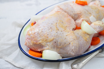 raw chicken legs with carrot and onion on dish