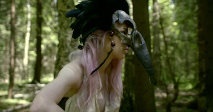 woman dressed in stylized costume of ancient wild shaman with helmet from bird skull
