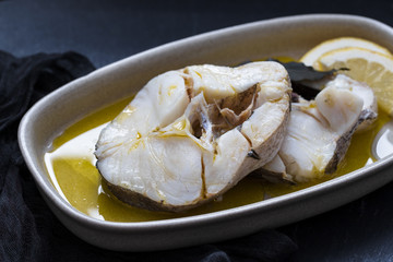 boiled fish with olive oil in dish on ceramic background