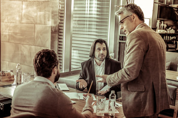 Concentrated grey-haired man listening to his colleagues