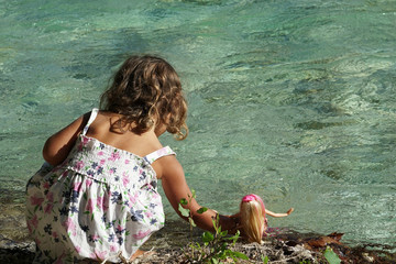 A little girl is bathing her doll in the Acheron River with its pristine nature in Epirus, Greece