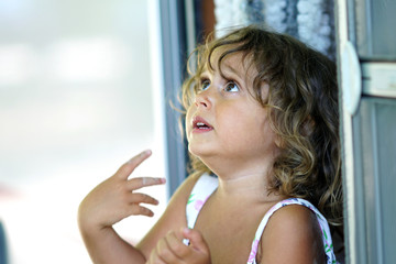 A three-year-old blond girl looks up