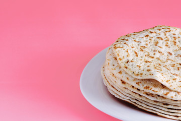 fried pancakes close-up on a white plate, dessert on a pink background, place for text