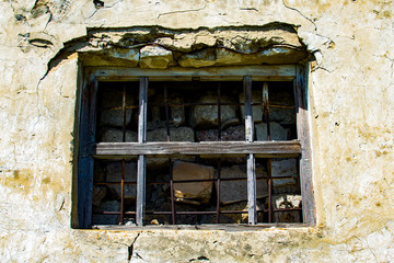 Window in the wall of an abandoned house. Old house. The ruins of the house. Window with bars.