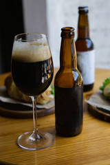 Pouring craft beer in a glass on a wooden table, dark background. Copy space