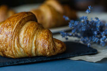 freshly baked croissants with dried flowers and parchment on grey table, close up 