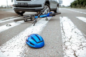 Naklejka na ściany i meble Scene of a road accident with car and broken bicycle lying on the pedestrian crossing. Helmet on the foreground