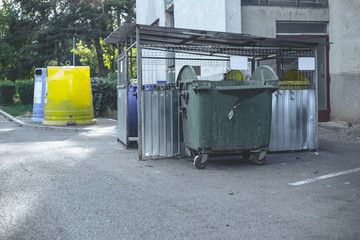 Garbage can area in a residential zone – Urban plastic trash bins of different colors lying next...